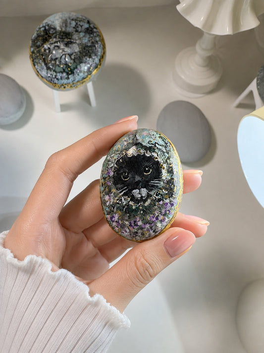 手のひらでそっと持つ、黒猫を描いた小さな石作品